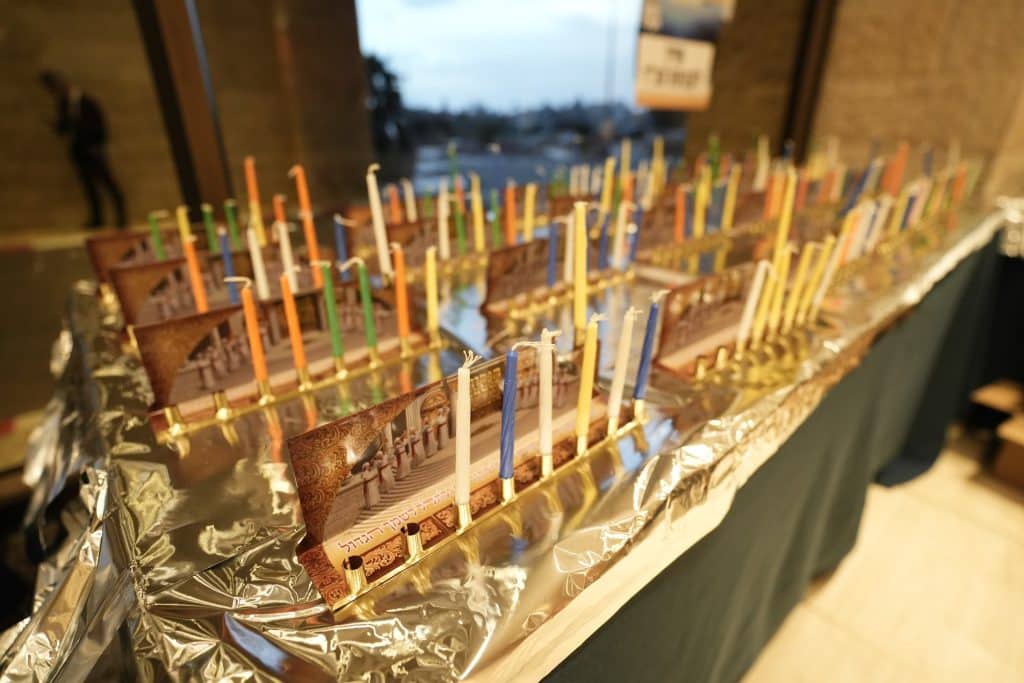 Dozens of menorahs sitting on aluminum foil and unlit